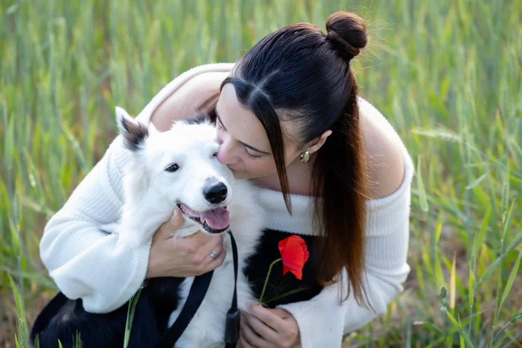 Chica abrazando a su Border Collie durante una sesión de fotografía familiar en un entorno natural.